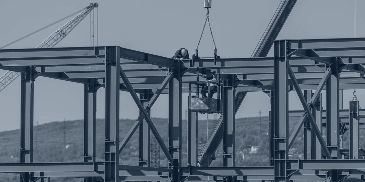 Ironworkers connecting a beam to a multi-story structural steel frame during erection.